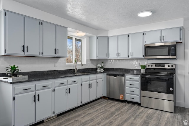 252 W Durfee St, Grantsville, UT 84029 - kitchen with appliances with stainless steel finishes, a sink, a textured ceiling, backsplash, and dark wood-type flooring