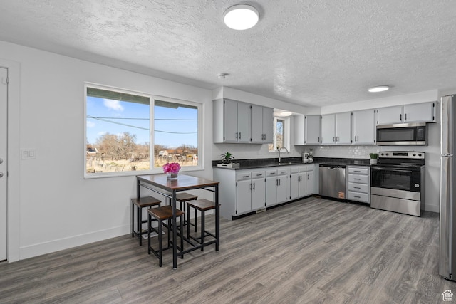 252 W Durfee St, Grantsville, UT 84029 - kitchen with stainless steel appliances, a textured ceiling, dark countertops, dark wood-style floors, and a sink
