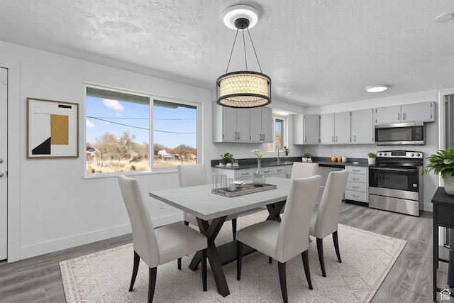 252 W Durfee St, Grantsville, UT 84029 - dining space featuring a textured ceiling, light wood-style flooring, baseboards, and a chandelier