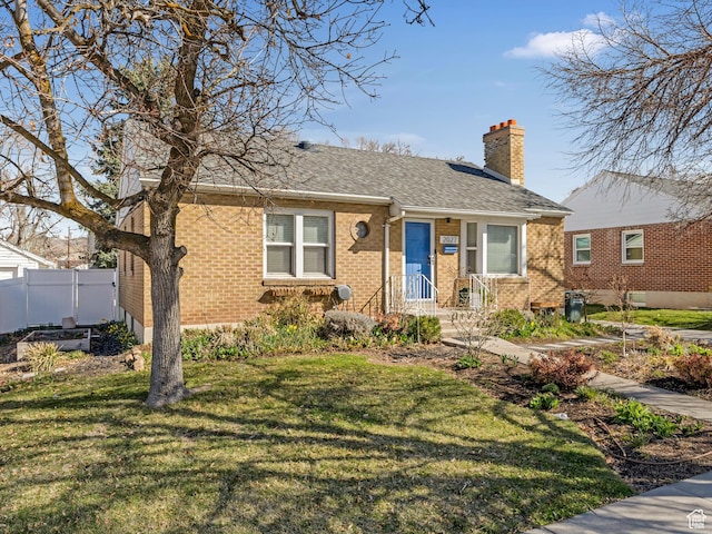 view of front of house with a front lawn, a chimney, fence, and brick siding