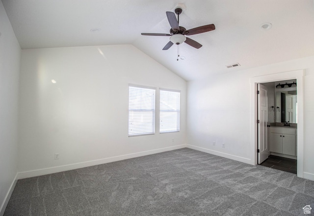 unfurnished bedroom with visible vents, baseboards, lofted ceiling, a sink, and dark colored carpet