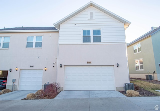 view of front of house featuring driveway, an attached garage, and central AC