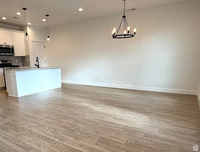 kitchen featuring baseboards, light wood-type flooring, a chandelier, and stainless steel appliances