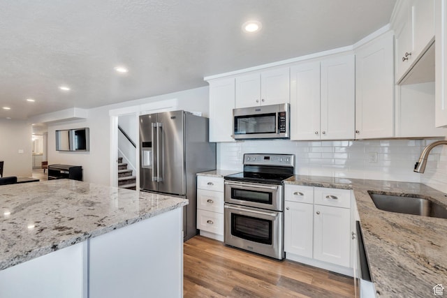 9844 N Faust Station Dr W, Eagle Mountain, UT 84005 - kitchen featuring white cabinets, a sink, light wood-type flooring, and appliances with stainless steel finishes