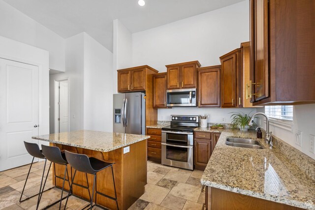 141 E Cottage Cv, Saratoga Springs, UT 84045 - kitchen featuring a kitchen breakfast bar, light stone countertops, appliances with stainless steel finishes, a sink, and a center island