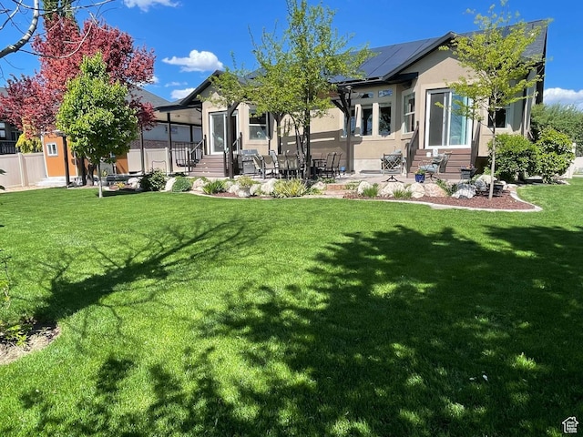 958 S Bridgecreek Ln, Layton, UT 84041 - rear view of house with entry steps, stucco siding, a yard, and roof mounted solar panels