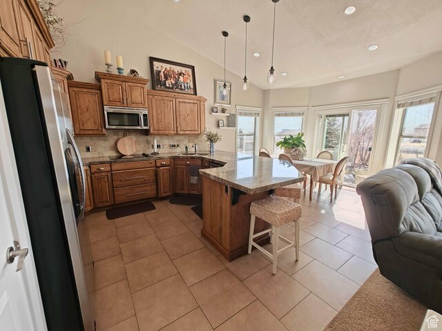 958 S Bridgecreek Ln, Layton, UT 84041 - kitchen with a peninsula, open floor plan, a breakfast bar area, brown cabinets, and stainless steel appliances