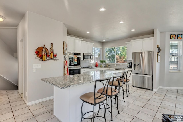 496 E Spruce Glen Rd, Murray, UT 84107 - kitchen with stainless steel appliances, light tile patterned floors, recessed lighting, a breakfast bar, and white cabinets