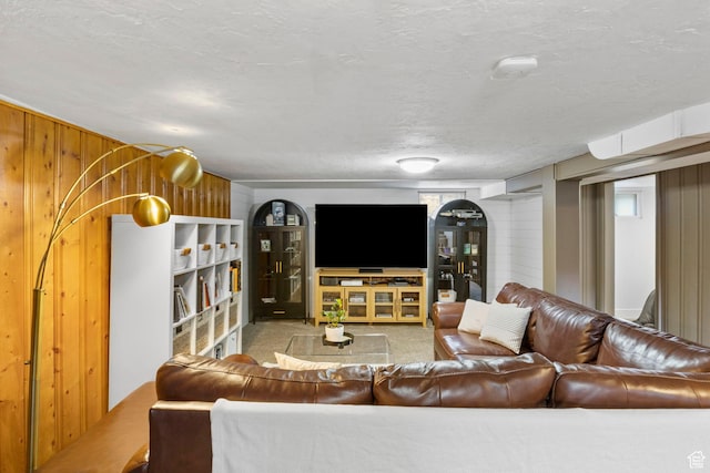 living area with carpet flooring, a textured ceiling, and wooden walls