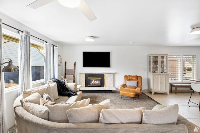 tiled living area featuring a ceiling fan and a premium fireplace