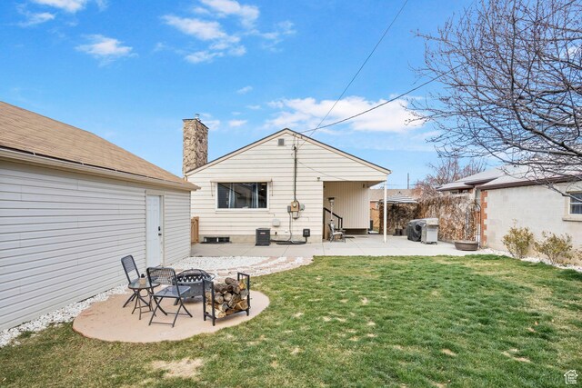 rear view of property featuring a chimney, a fire pit, a yard, and a patio area