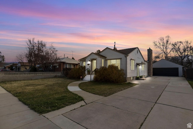 view of front of property featuring an outdoor structure, fence, a lawn, a detached garage, and a chimney