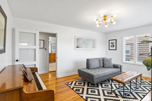 living room with a notable chandelier, baseboards, and light wood finished floors