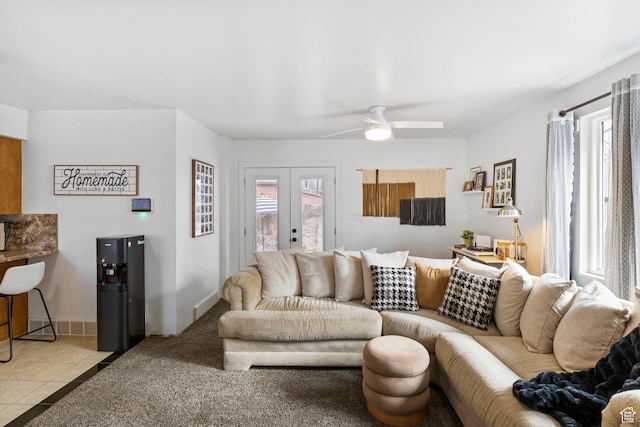 carpeted living room featuring french doors, a ceiling fan, baseboards, and tile patterned flooring