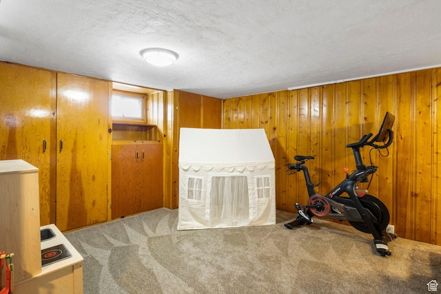 workout room featuring carpet, wood walls, and a textured ceiling