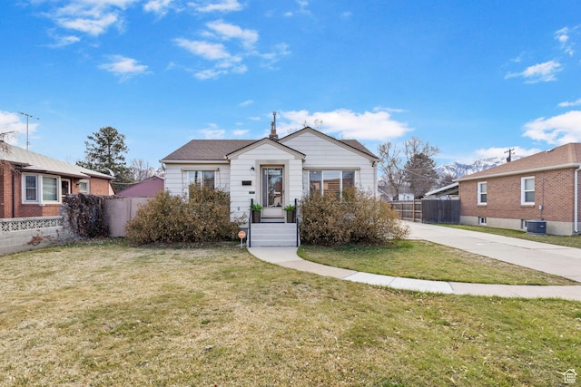 bungalow-style home featuring fence, concrete driveway, and a front yard