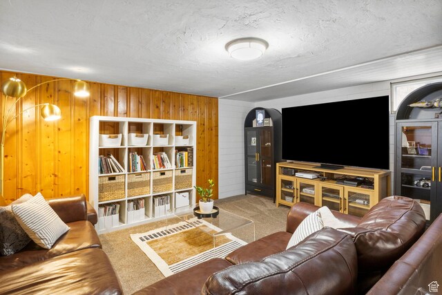 living area with carpet floors, a textured ceiling, and wooden walls