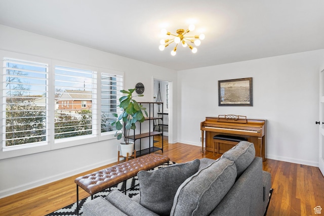 living area with baseboards, wood finished floors, and a chandelier