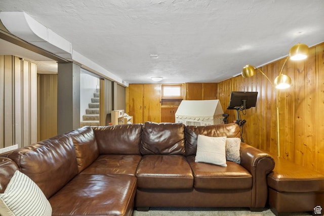 living area with wooden walls, stairway, and a textured ceiling