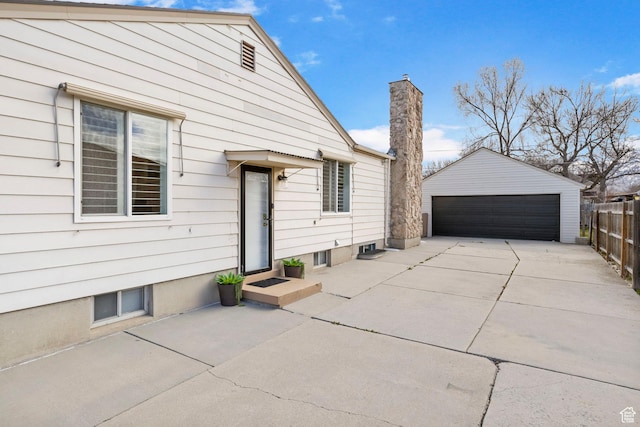 exterior space featuring an outbuilding, a garage, fence, and a chimney