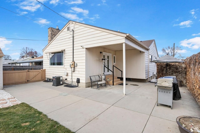 rear view of property featuring a chimney, fence, entry steps, and a patio area