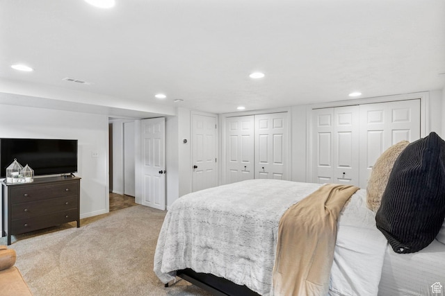 bedroom with multiple closets, visible vents, baseboards, recessed lighting, and light colored carpet