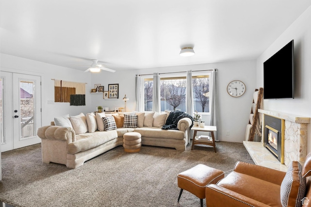 carpeted living room with french doors, a glass covered fireplace, and a ceiling fan