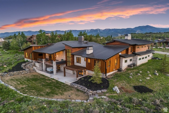 7290 Foxglove Ct, Park City, UT 84098 - back of house at dusk with a patio, metal roof, a mountain view, and a chimney