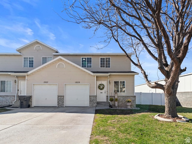 view of front of house featuring fence, stone siding, driveway, a front lawn, and a garage
