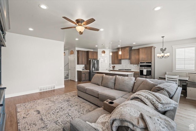 1321 E Daffodil Ct N Unit 155, Layton, UT 84040 - living room with light wood-style flooring, visible vents, baseboards, recessed lighting, and ceiling fan with notable chandelier