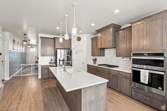 1321 E Daffodil Ct N Unit 155, Layton, UT 84040 - kitchen featuring light countertops, stainless steel appliances, a center island with sink, a sink, and light wood-style floors