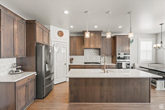 1321 E Daffodil Ct N Unit 155, Layton, UT 84040 - kitchen featuring light countertops, a sink, light wood finished floors, stainless steel appliances, and decorative light fixtures