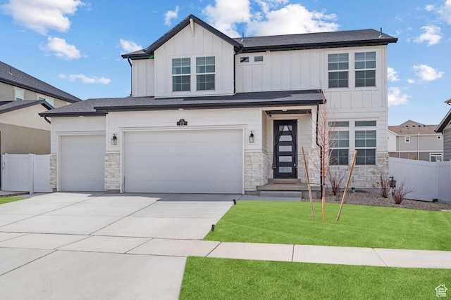 view of front of house with fence, stone siding, board and batten siding, driveway, and a front lawn