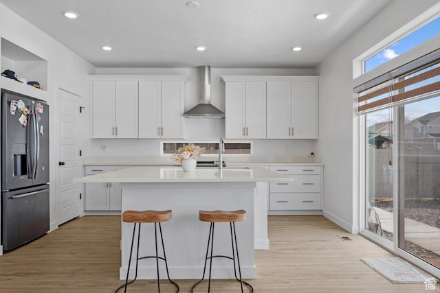217 S Buckhorn Bath Ave W, Saratoga Springs, UT 84045 - kitchen with light countertops, stainless steel fridge with ice dispenser, wall chimney exhaust hood, a center island with sink, and white cabinets