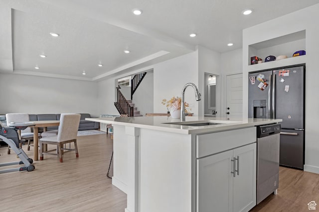 217 S Buckhorn Bath Ave W, Saratoga Springs, UT 84045 - kitchen with light countertops, stainless steel appliances, a center island with sink, a sink, and light wood-type flooring