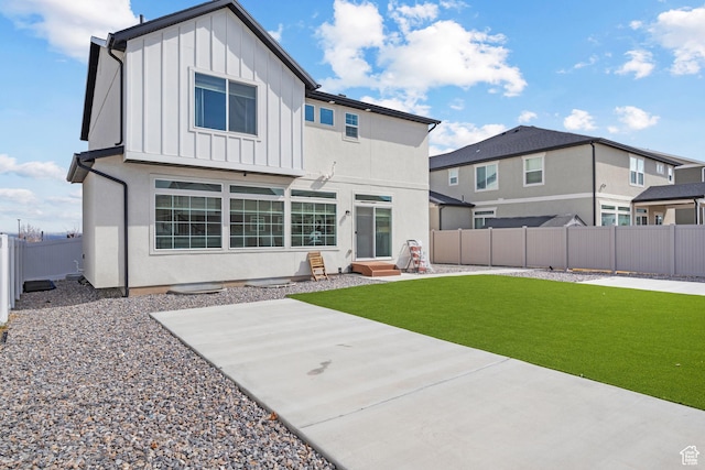 217 S Buckhorn Bath Ave W, Saratoga Springs, UT 84045 - back of house featuring stucco siding, a fenced backyard, board and batten siding, entry steps, and a lawn