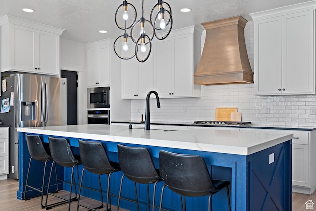 1807 S Bridle Path Loop, Lehi, UT 84043 - kitchen with light wood-style floors, a center island with sink, appliances with stainless steel finishes, decorative backsplash, and custom exhaust hood