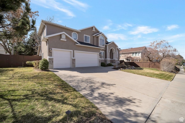 traditional-style home featuring concrete driveway, stucco siding, fence, an attached garage, and a front yard