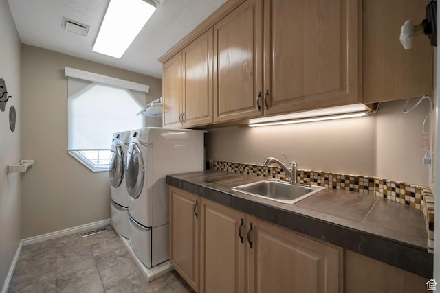 laundry room with a sink, baseboards, independent washer and dryer, visible vents, and cabinet space