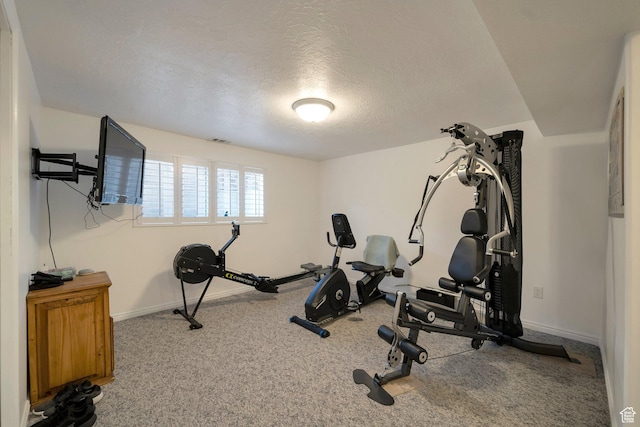 exercise room featuring visible vents, carpet, baseboards, and a textured ceiling