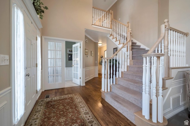 foyer featuring a wainscoted wall, ornamental molding, stairway, and wood finished floors