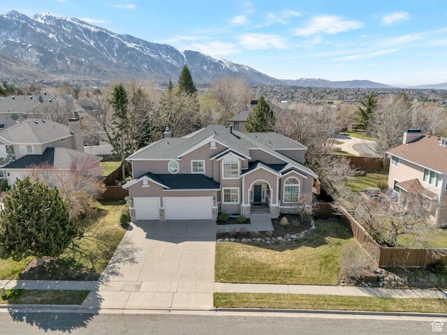 view of front of house featuring stucco siding, driveway, a front yard, a mountain view, and fence private yard