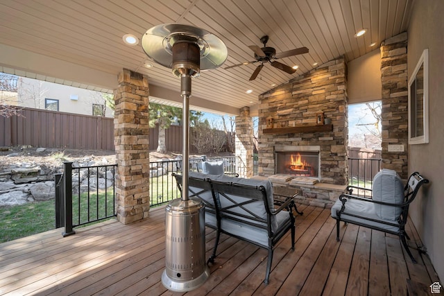 wooden deck featuring an outdoor stone fireplace and ceiling fan