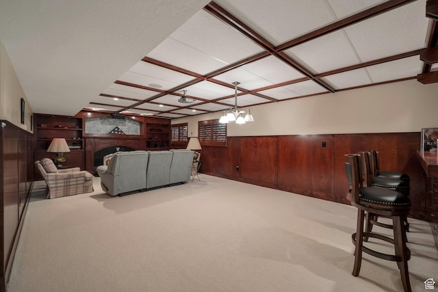 carpeted living room with a wainscoted wall, a fireplace, coffered ceiling, and wooden walls