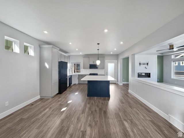 kitchen featuring light countertops, stainless steel microwave, a center island, dark wood-style floors, and freestanding refrigerator