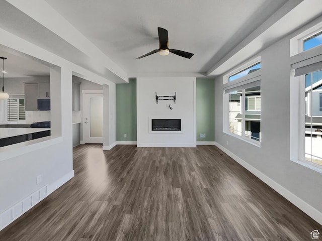 unfurnished living room featuring a ceiling fan, dark wood-style floors, baseboards, and a fireplace