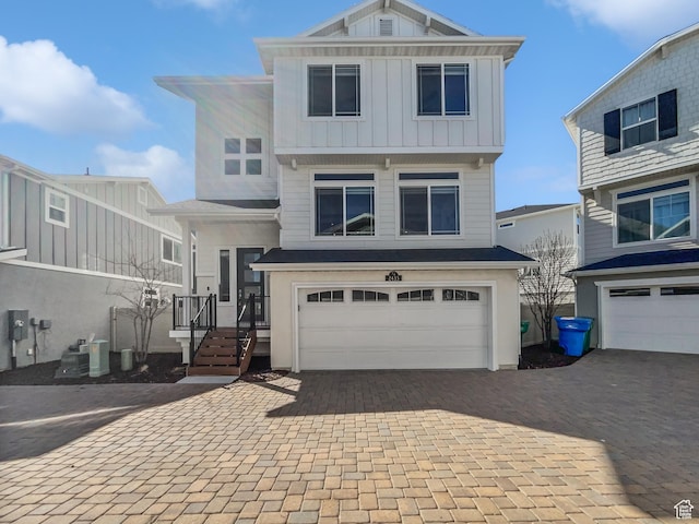 view of front of home with cooling unit, decorative driveway, a garage, and board and batten siding