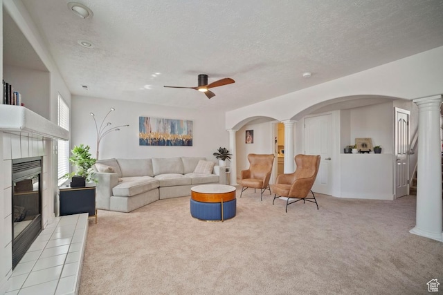 28 E 1400 N, Mapleton, UT 84664 - living room with a tiled fireplace, a ceiling fan, decorative columns, arched walkways, and light carpet