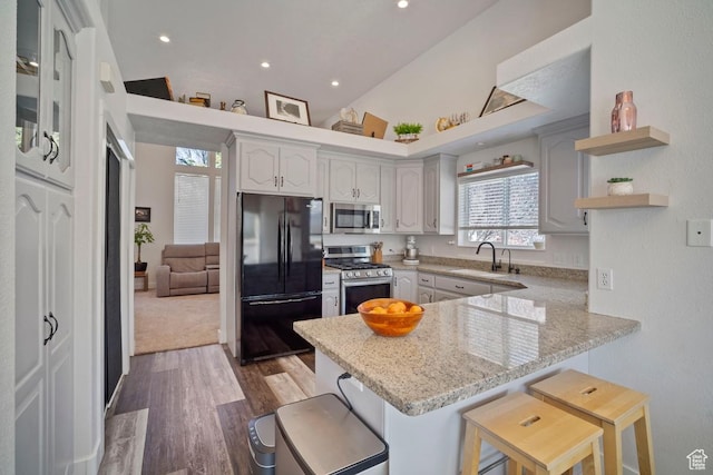 28 E 1400 N, Mapleton, UT 84664 - kitchen featuring a breakfast bar area, stainless steel appliances, a sink, a peninsula, and wood finished floors