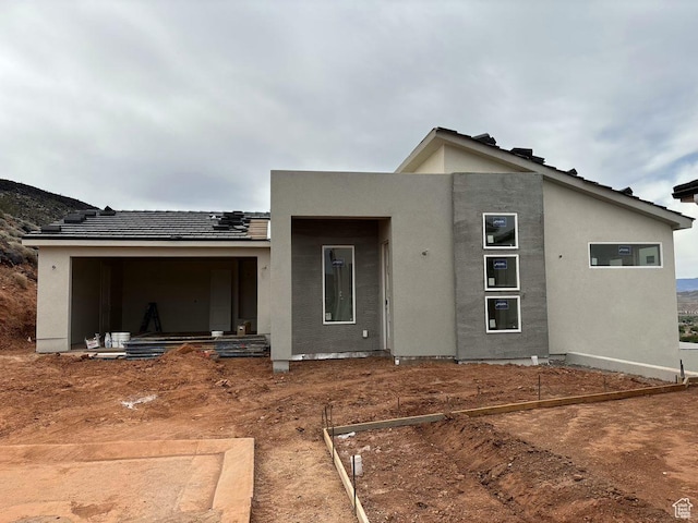 rear view of house featuring a tile roof and stucco siding